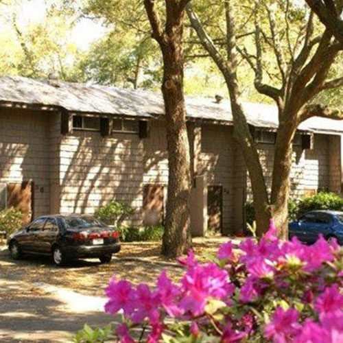 Exterior view of apartment building shaded by trees.